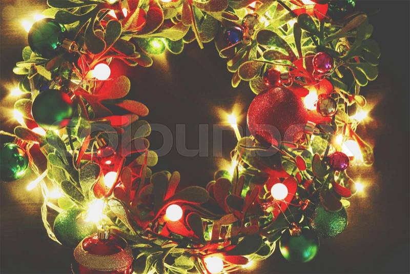 Greeting Season concept.Christmas wreath with decorative light on dark wood background, stock photo