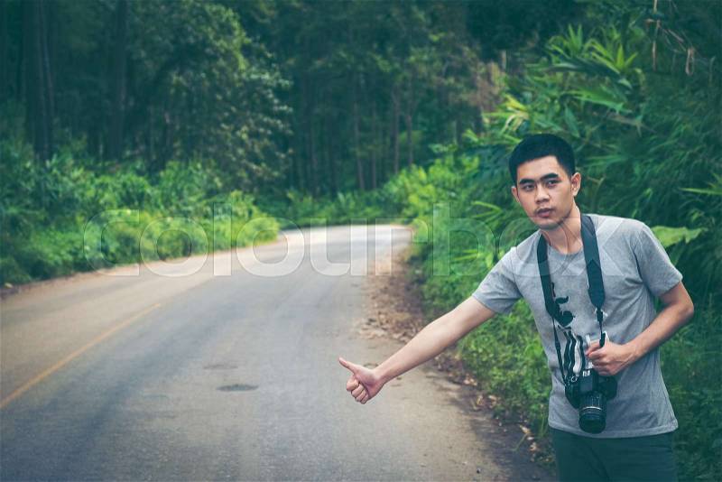 Hitchhiking traveler try to stop car on the mountain road, stock photo