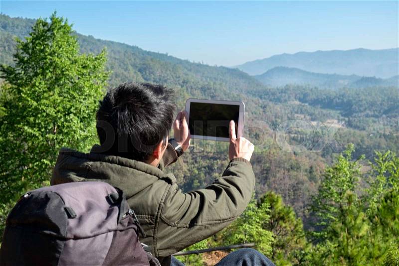 Man Traveler with tablet camera and backpack hiking outdoor Travel Lifestyle and Adventure concept, stock photo