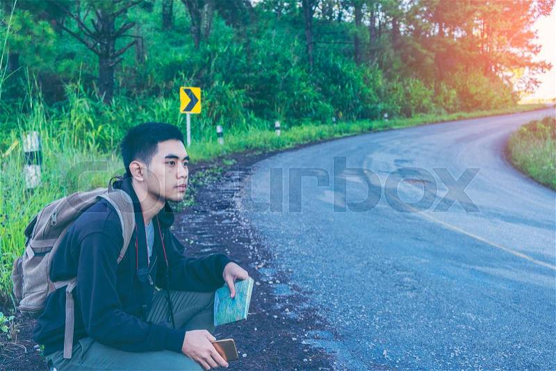 Man with Backpacks in casual Travel Clothes walking along road ,Road hitch-hiking. Traveler sitting at the highway hitching, stock photo