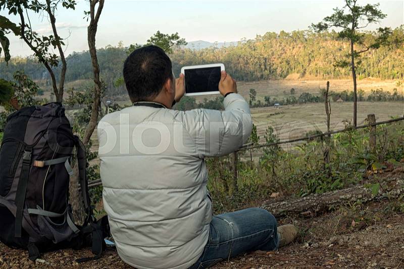Man Traveler with Tablet camera and backpack hiking outdoor Travel Lifestyle and Adventure concept, stock photo