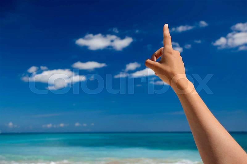 Female hand against a beautiful blue sky pointing somewhere, stock photo
