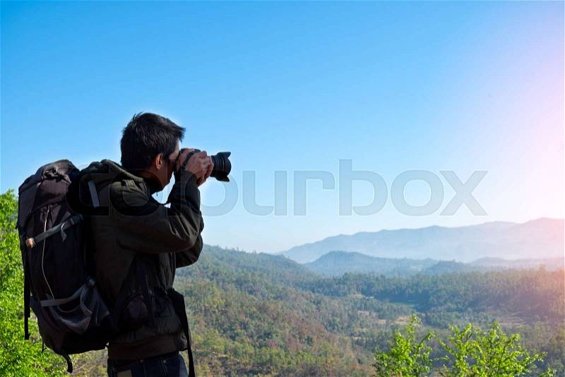 Man Traveler with photo camera and backpack hiking outdoor Travel Lifestyle and Adventure concept, stock photo
