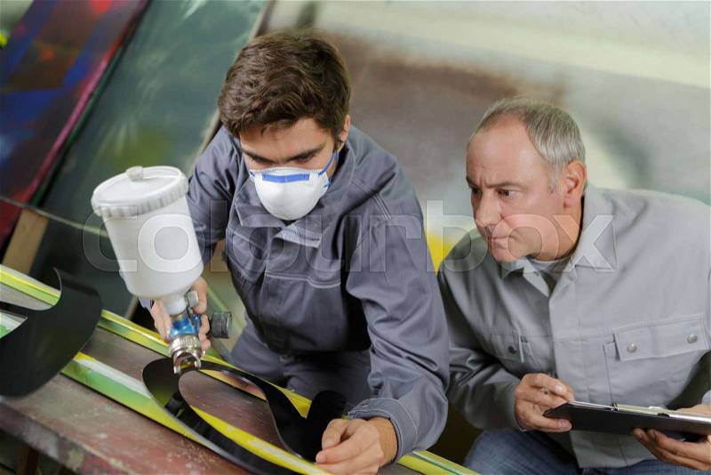 Worker with protective mask painting in a factory, stock photo