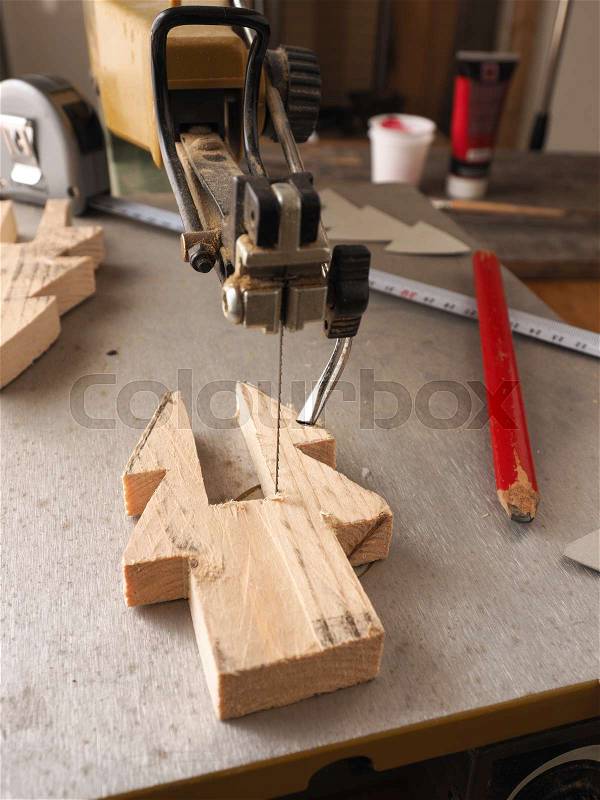 Wood working concept with a scroll saw, making a wooden Christmas tree decoration, stock photo