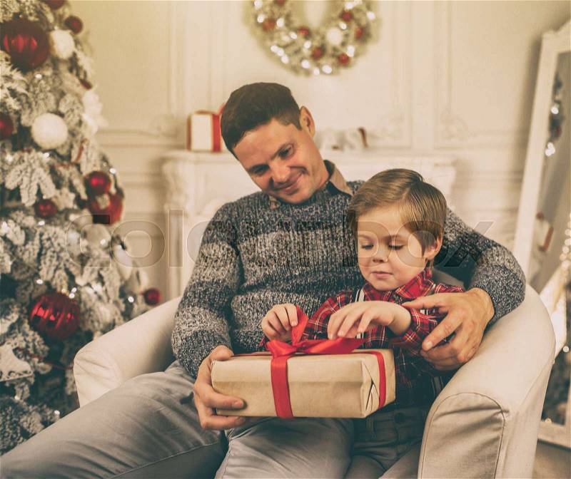 Father and son unwrapping presents on Christmas evening, stock photo