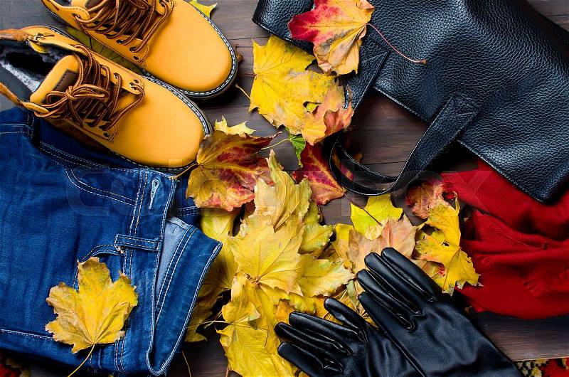 Collage of Feminine clothing and accessories. jeans, shoes, scarf, gloves, bag and glasses for autumn day in yellow and orange color on dark background. with fall leaves. , stock photo