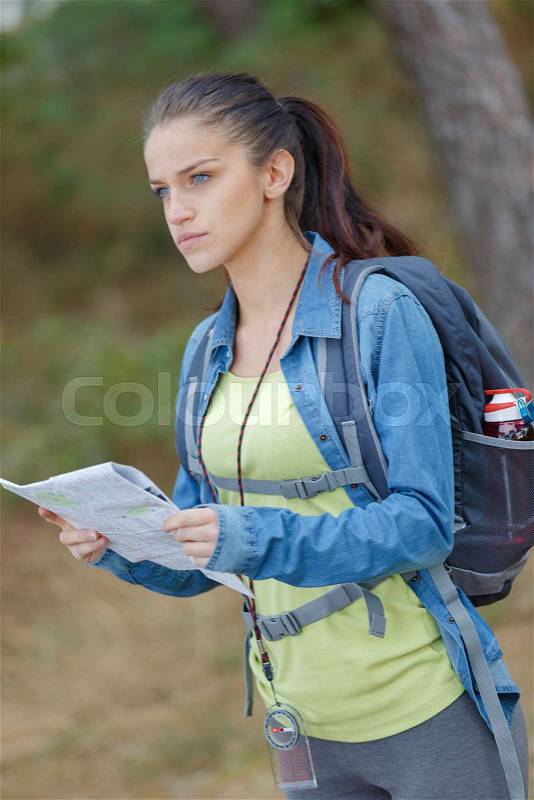 Young female hiker holding a map, stock photo