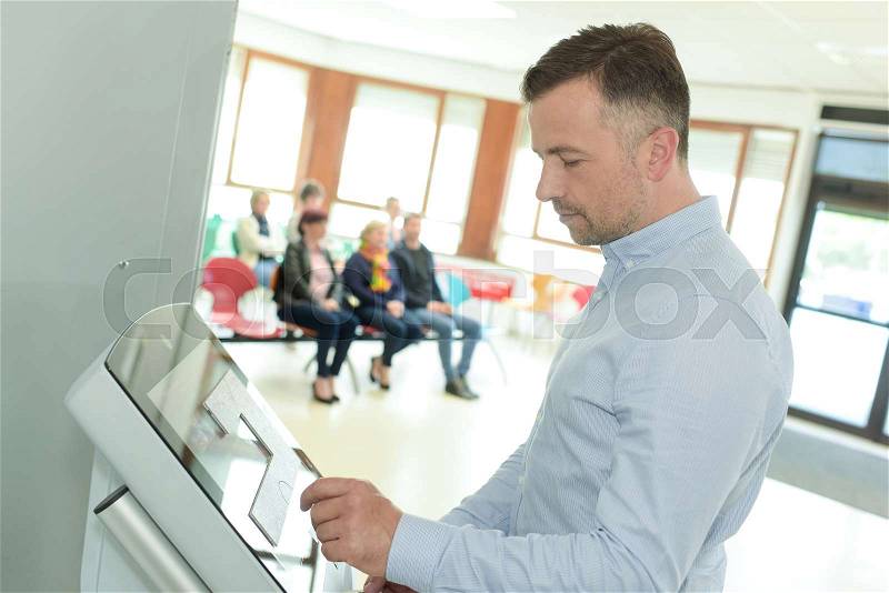 Man doing check-in at self help desk in the airport, stock photo
