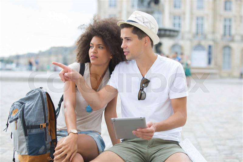 Young couple of tourists looking at tablet screen outdoors, stock photo