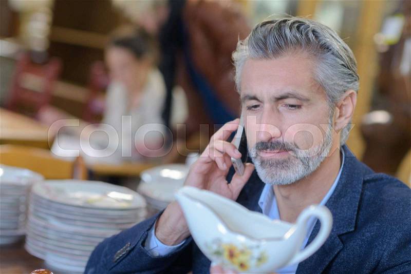 Man checking on the phone the value of an antiques, stock photo