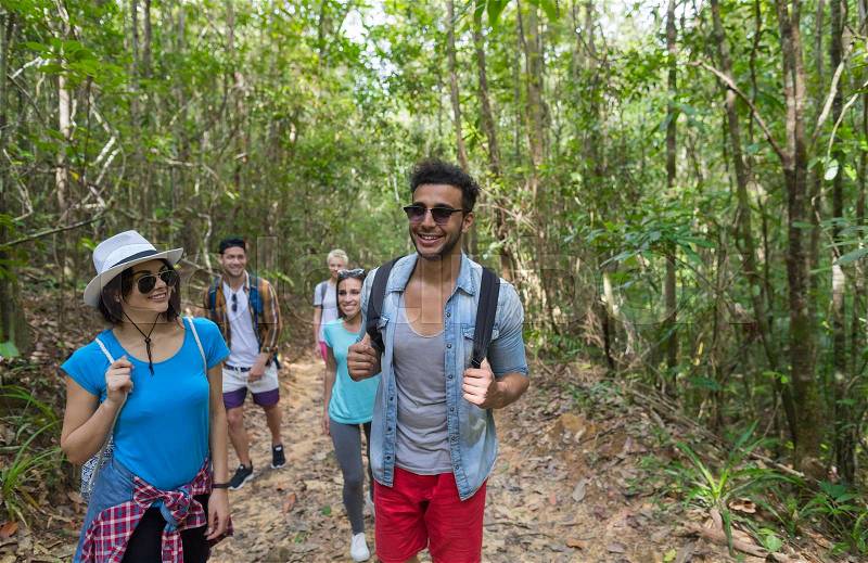 People Group With Backpacks Trekking On Forest Path, Young Men And Woman On Hike Mix Race Tourists Hiking, stock photo