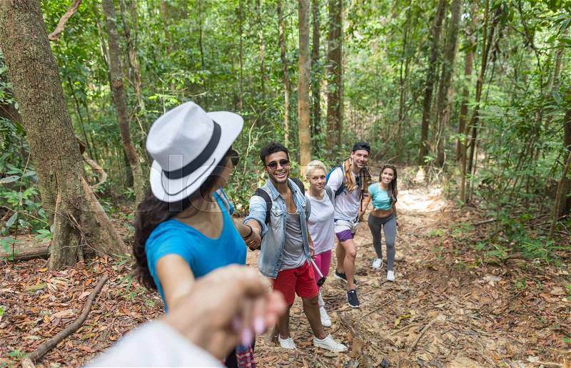 People Group With Backpacks Trekking On Forest Path Holding Hands Helping, Mix Race Young Men And Woman On Hike Tourists Adventure Activity, stock photo