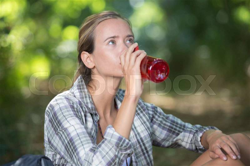 Young hiker drinking water at mountain valley, stock photo