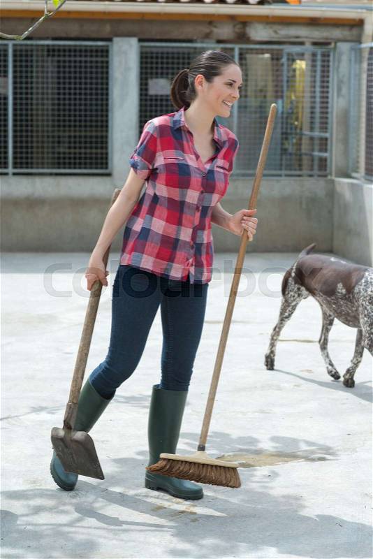 Girl sweeping dog pen, stock photo
