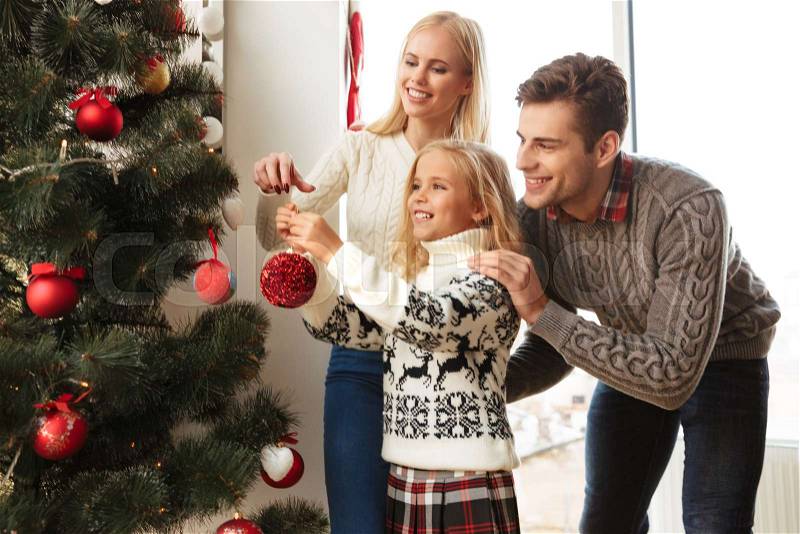 Happy family decorating christmas tree at home, stock photo