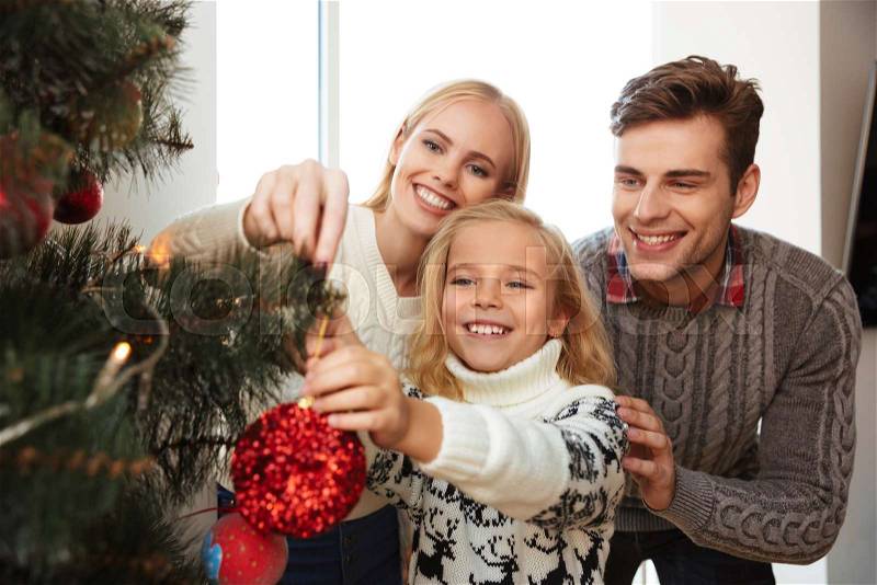 Close-up photo of happy family decorating christmas tree at home, stock photo