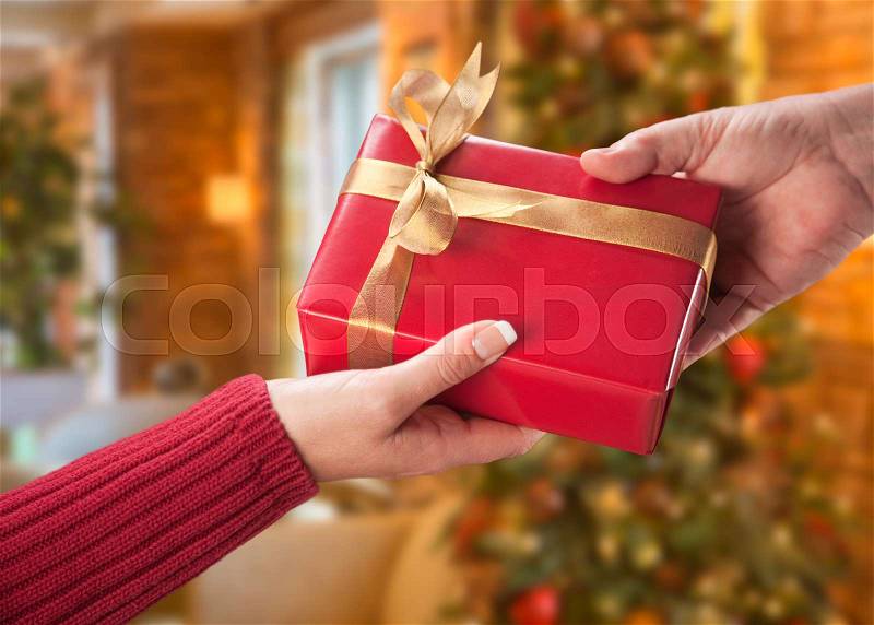 Man and Woman Gift Exchange in Front of Decorated Christmas Tree, stock photo