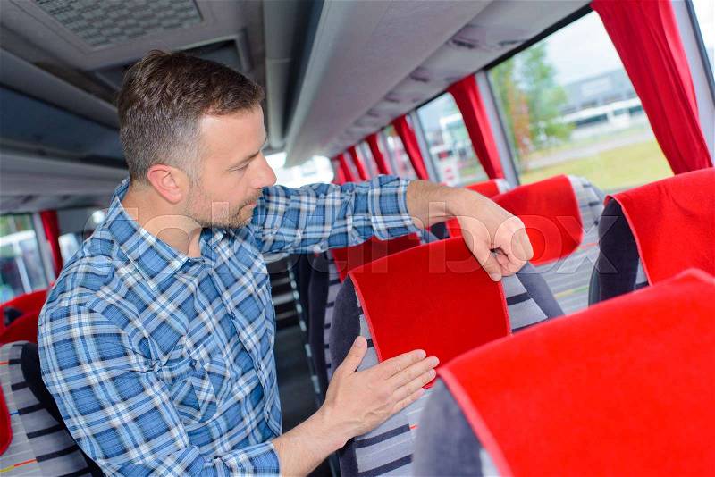 Man arranging head rest cover on bus, stock photo