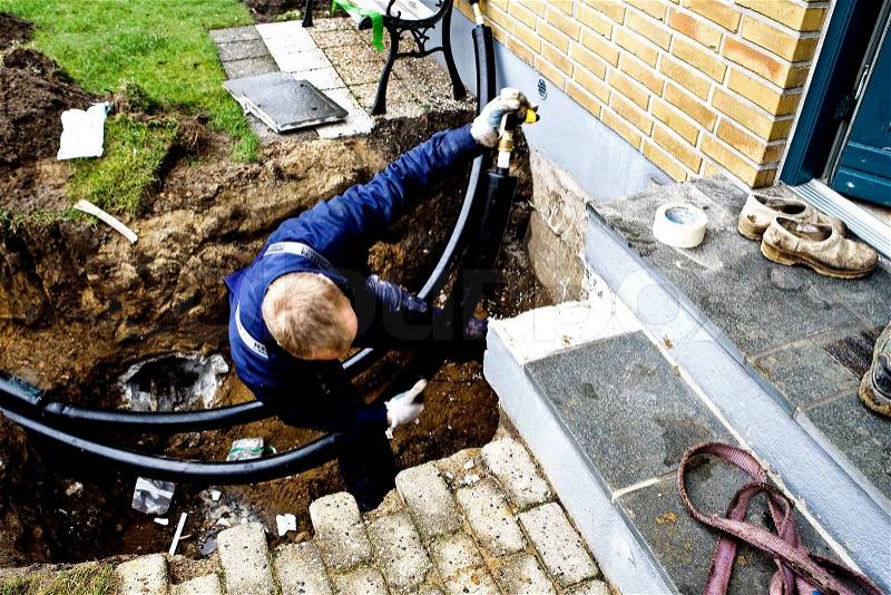 Works leads district heating pipes up to property, stock photo