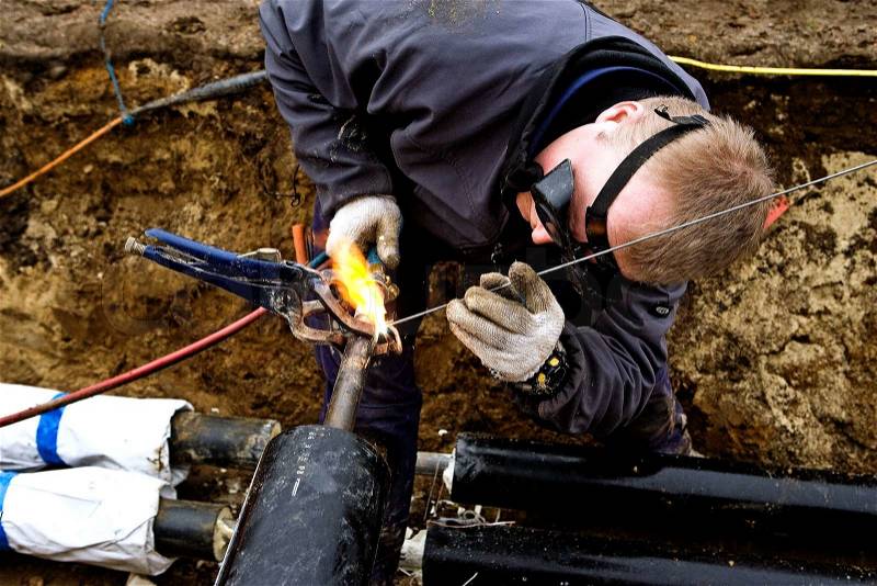 Works welder district in the ground with goggles, stock photo