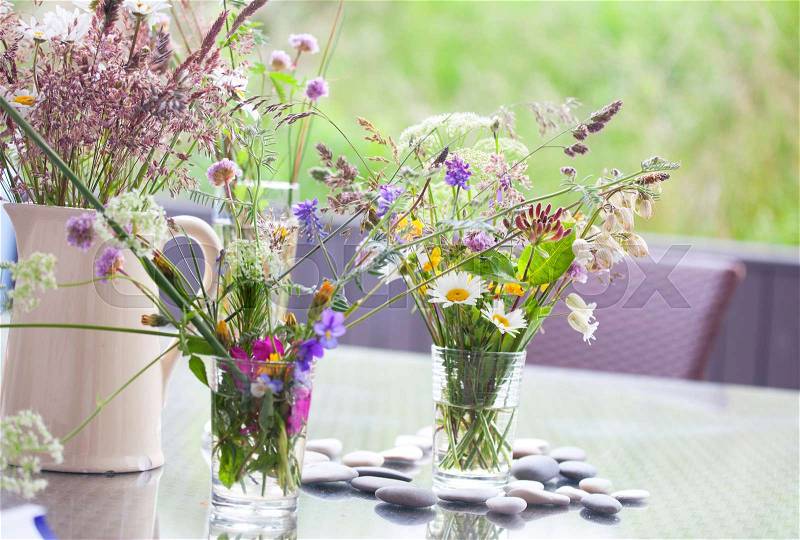 Picked wild flowers with colorful flowers in a vase and glasses on a table decorated, stock photo