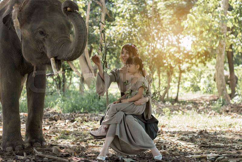 Portrait art of beautiful woman and girl playing with elephants in nature, stock photo