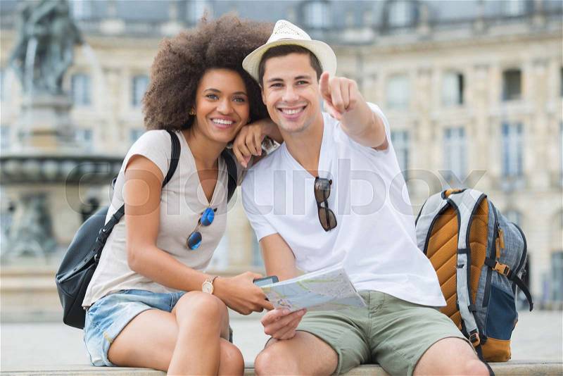 Young tourists pointing at a sight in the city, stock photo