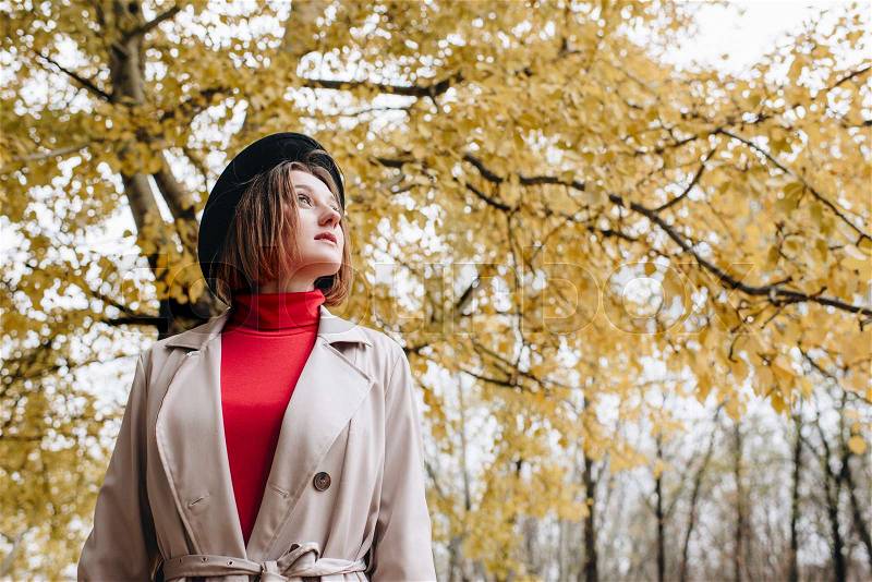 Young beautiful woman in trench coat at autumn park, stock photo