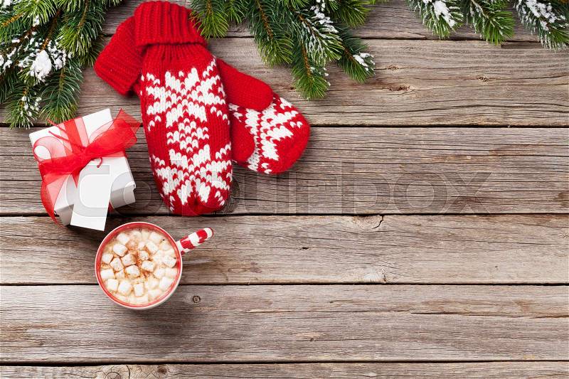 Christmas background with fir tree, mittens, hot chocolate and marshmallow on wooden table. Top view with copy space, stock photo