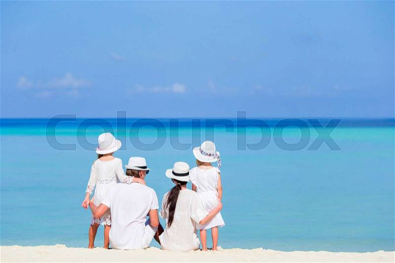 Back view of a happy family in white on the beach, stock photo