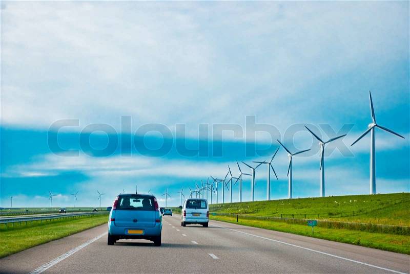 Cars on a highway with wind turbines, stock photo