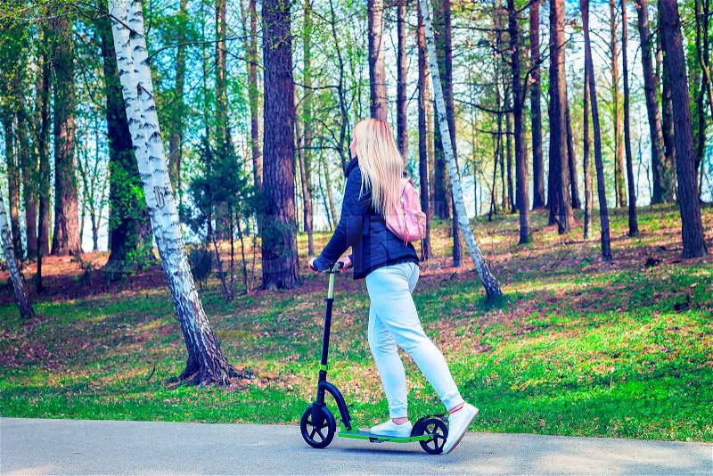 Young woman on push scooter in park of Druskininkai, Lithuania, stock photo