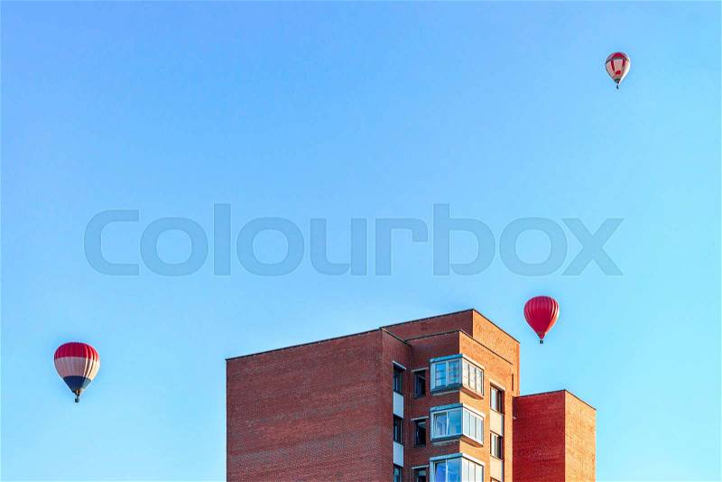 Red air balloons flying over the residential house building in the city, stock photo