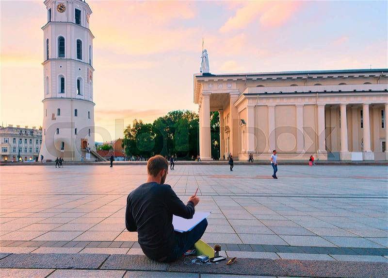 Man painting Cathedral Square and Bell tower in the historical city center in Vilnius, Lithuania. At sunset, stock photo