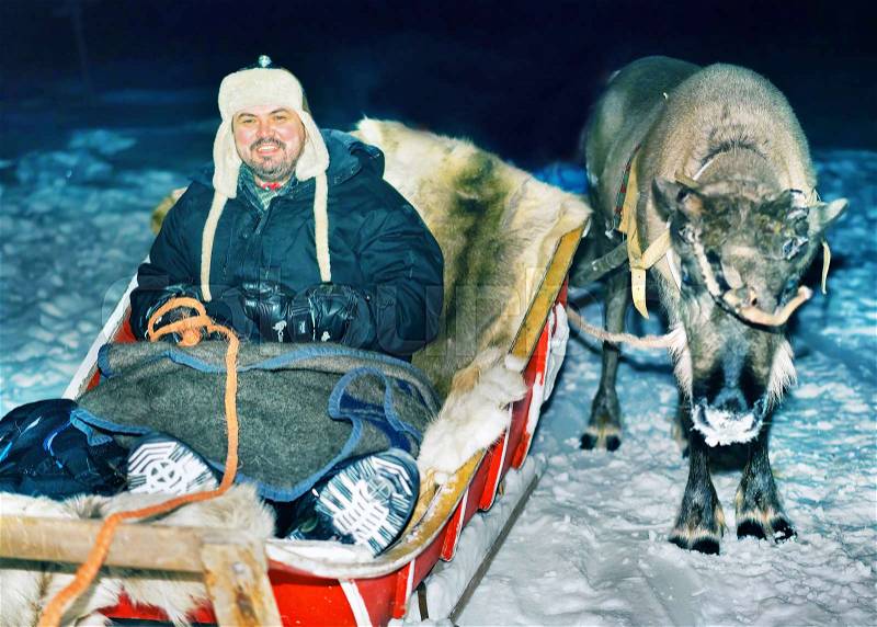 Man with reindeer sleigh at night safari in the forest, Rovaniemi, Lapland, Finland. Toned, stock photo