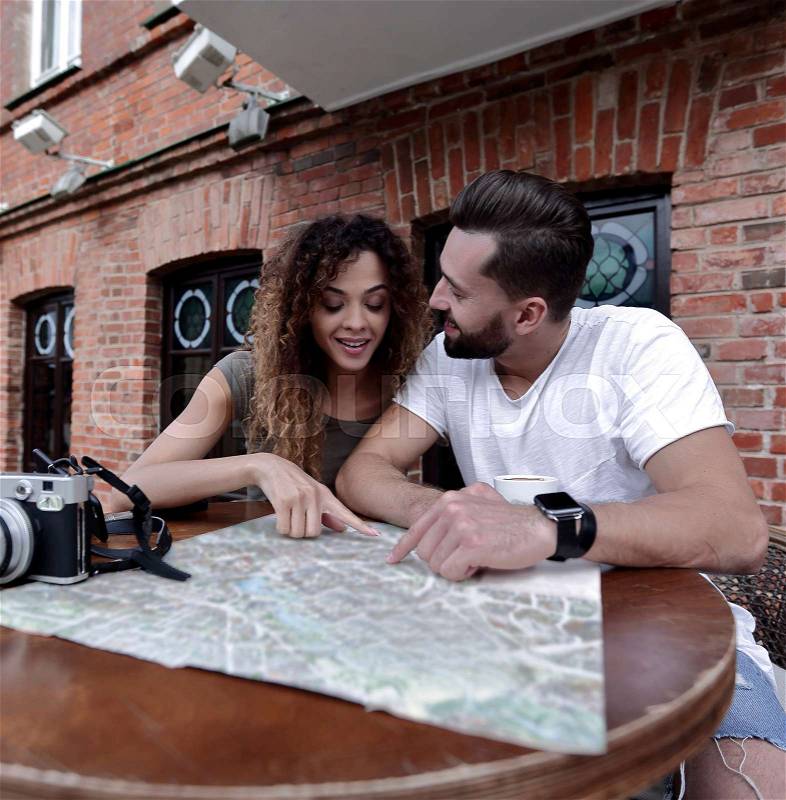 Couple in an outdoor cafe using map and planning itinerary, stock photo