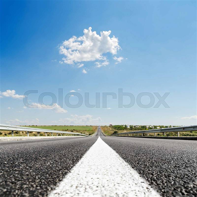 White line on asphalt road closeup and blue sky with clouds, stock photo