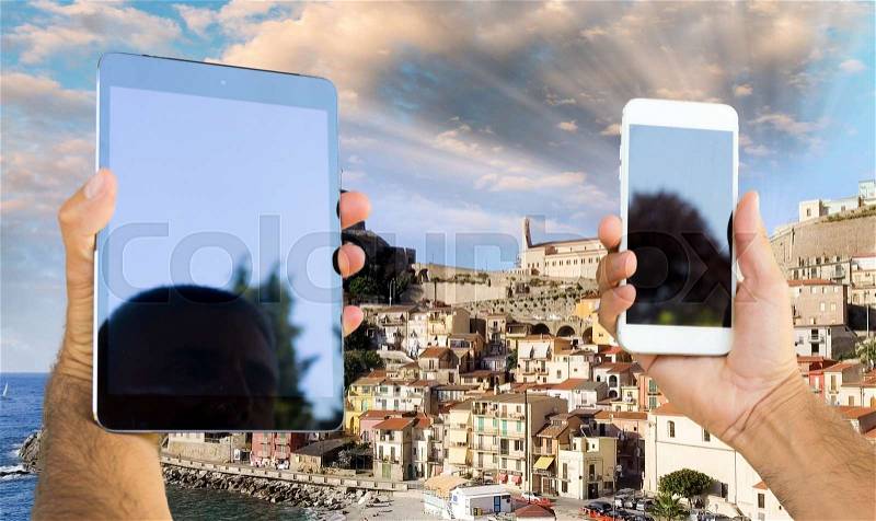 Smartphone and tablet taking pictures of Mediterranean town skyline, stock photo