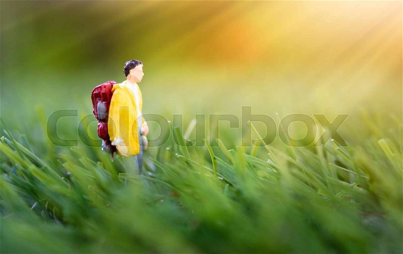 Miniature people,backpack traveler morning walk in nature green meadow background, stock photo