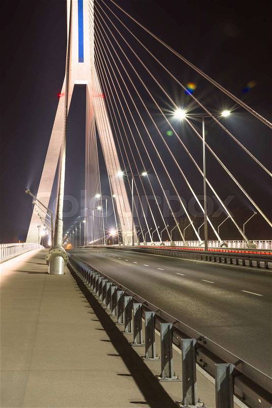 Highway going through a cable-stayed bridge with big steel cables, close-up in the night, stock photo