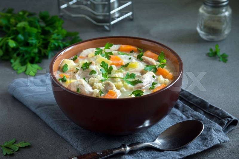 Chicken Soup. Homemade fresh creamy soup with chicken, vegetables and greens in bowl close up, stock photo