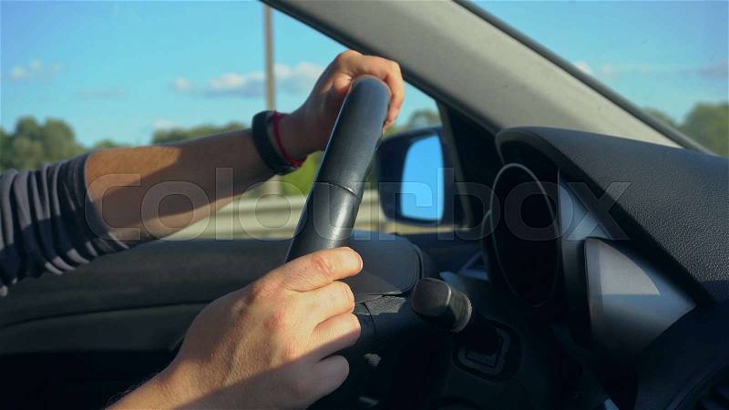 Inside a car. A man\'s hands on the steering wheel. Close-up shot, stock photo