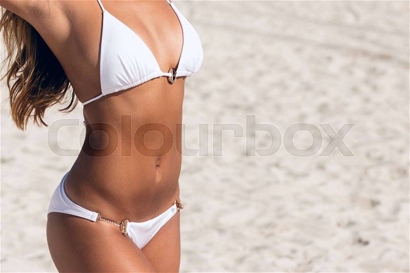 Close-up of fit, sexy bikini stomach abs. Woman with beautiful body on a tropical beach, stock photo