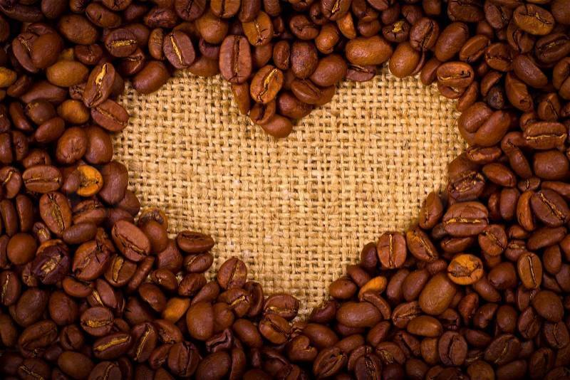 Heart shape created with coffee beans on a sacking background, stock photo