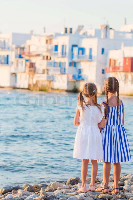 Adorable little girls at Little Venice the most popular tourist area on Mykonos island, Greece. Back view of beautiful kids look at Little Venice background, stock photo