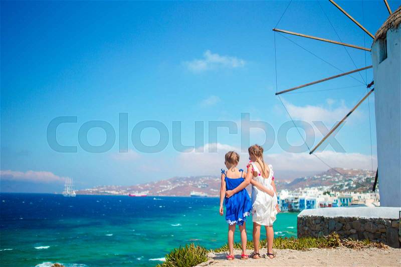 Adorable little girls with amazing view on Little Venice the most popular tourist area on Mykonos island, stock photo