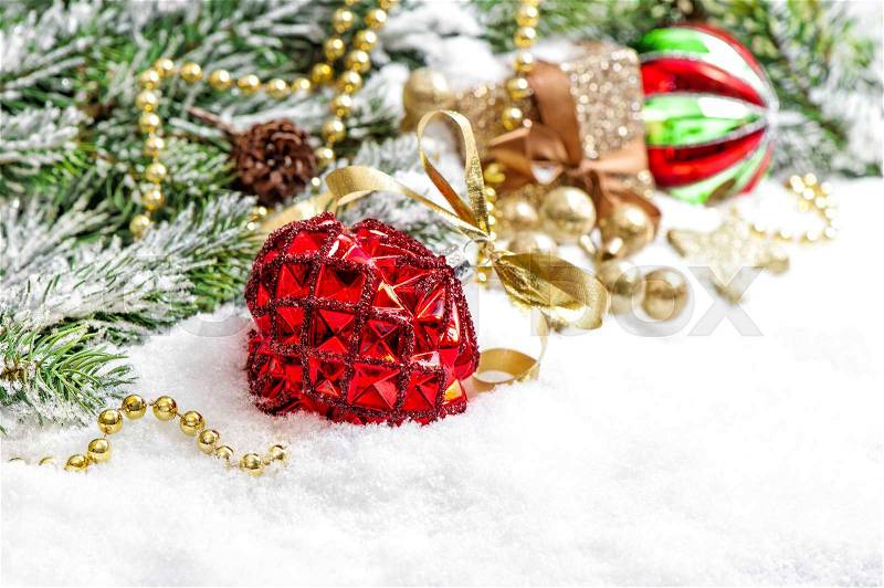 Christmas tree branches with red bauble and golden decoration on white snow background, stock photo