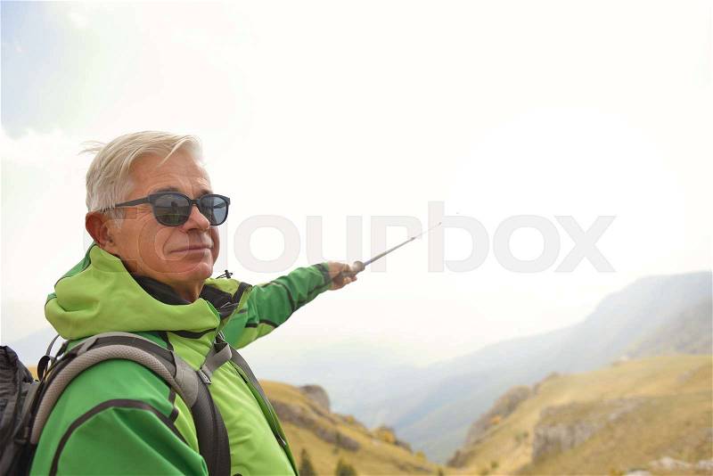 Man on top of the mountain pointing at something, stock photo