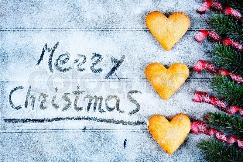 Shooting from above an antique wooden table covered with snow with the words Merry Christmas, stock photo